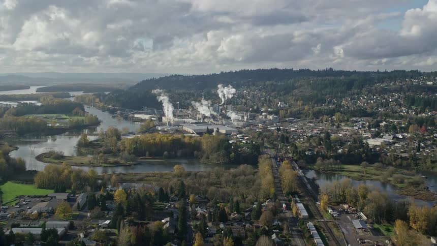 Aerial panorama of a factory in the midst of an urban city on the edge of lakes and surrounded by nature
