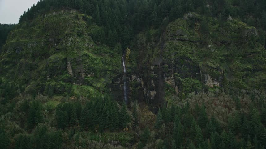 A small waterfall in the middle of a mountain full of trees