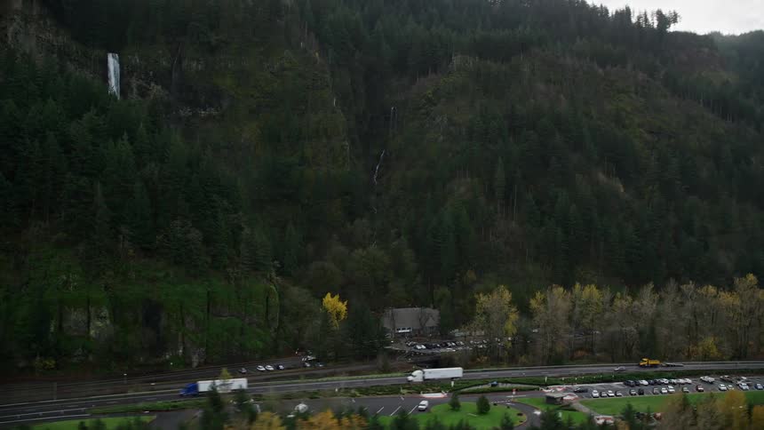 A waterfall is near the highway filled with traffic