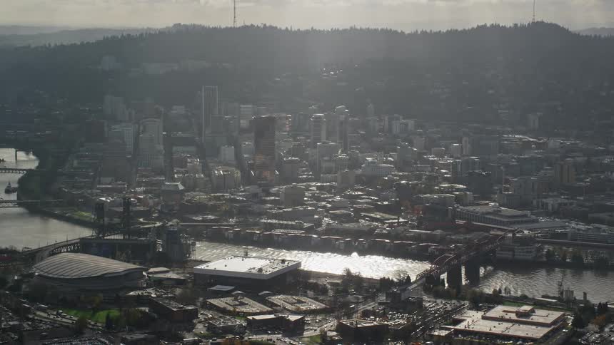 An aerial view captures downtown skyscrapers lining the willamette river as seen from the moda center in the lloyd district on a cloudy autumn day