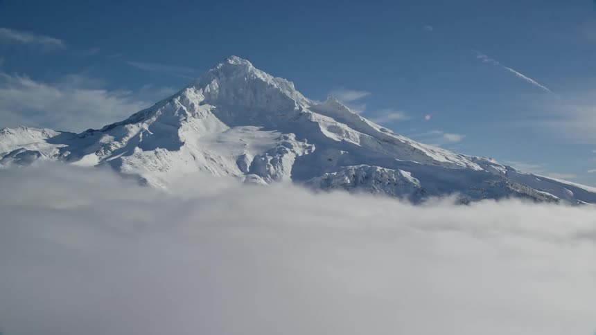 Mountain covered in snow and above the clouds with a view of the blue sky