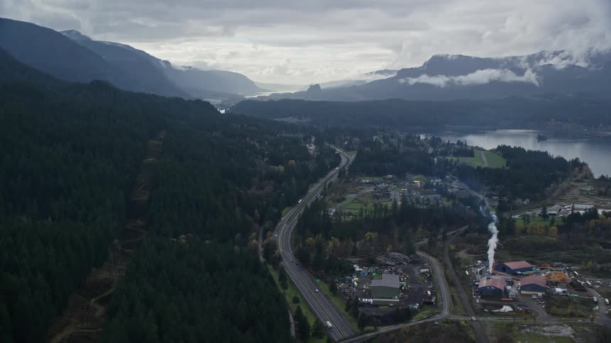 Aerial of a small neighborhood on the banks of a river surrounded by mountains and forests