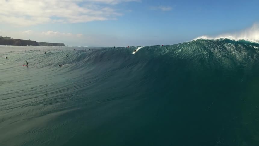 One of several surfers in the ocean catches a wave
