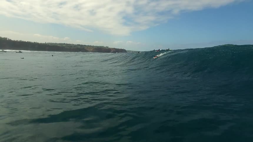 The water is full of surfers one is racing a wave to shore