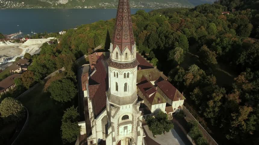 A tall tower on a building has trees all around it