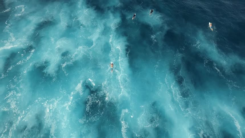 People travel in the blue water below on surfboards