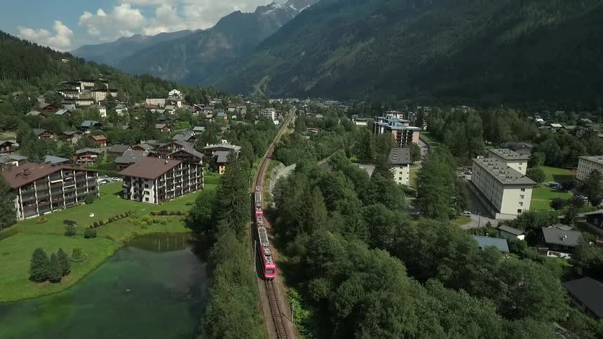 A train travels through a town by a mountain range
