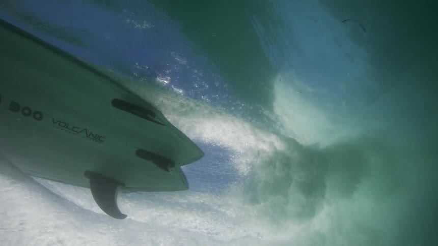 Underwater view of a surfboard catching a wave