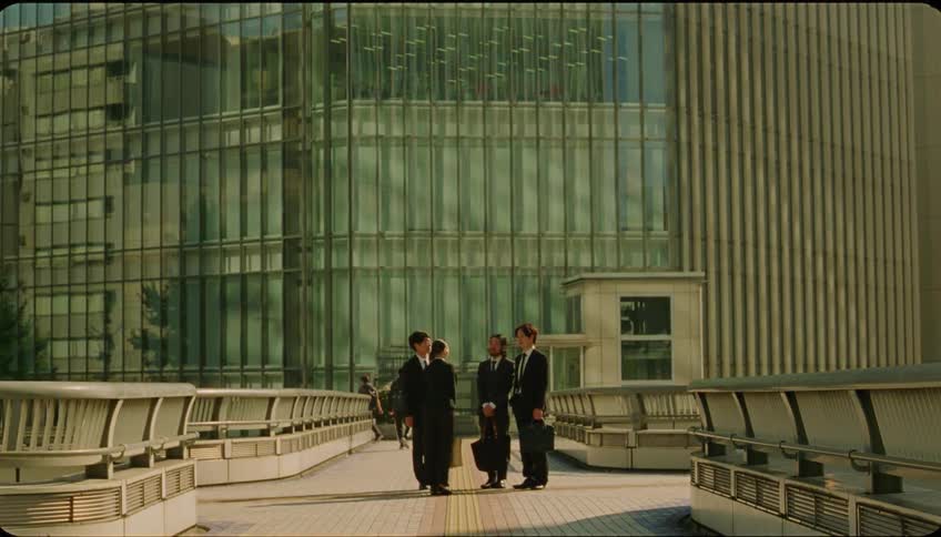 A group of people in suits are talking and a woman says goodbye and walks forward letting down her hair