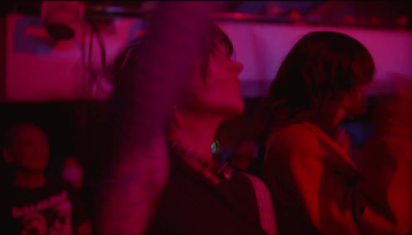 Woman dancing enthusiastically among the crowd at a concert in an indoor venue