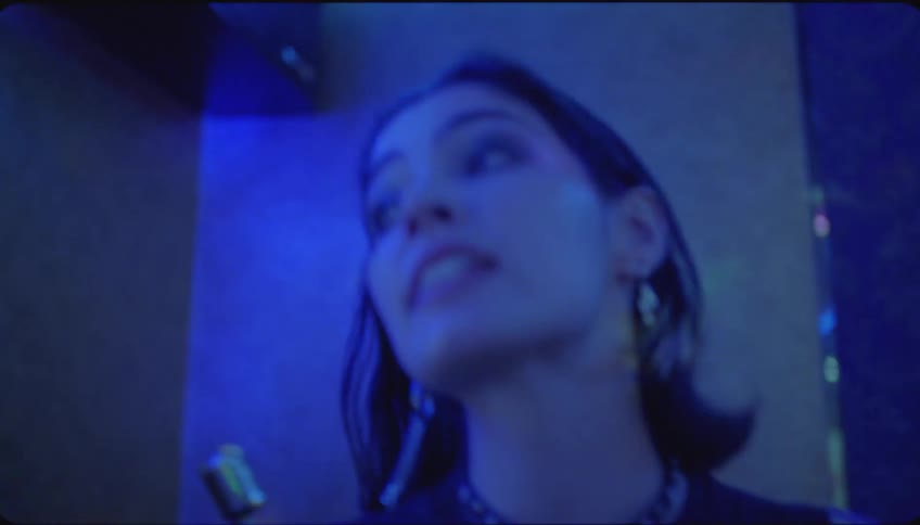 A young woman is singing in a night club and the audience who is sitting sings together