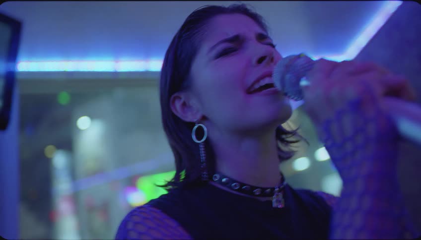Portrait of a young woman singing in a nighttime indoor setting