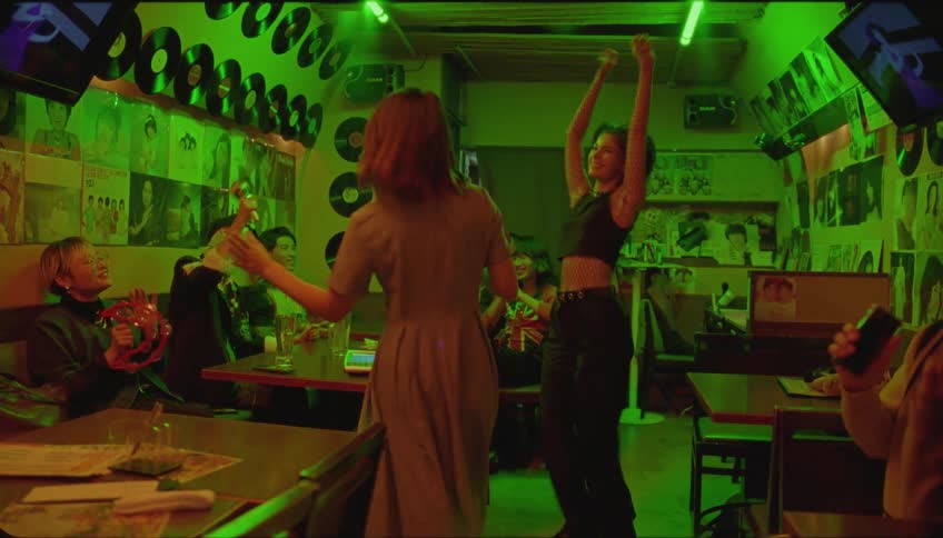 Two females dancing in a restaurant and others cheer them while seated