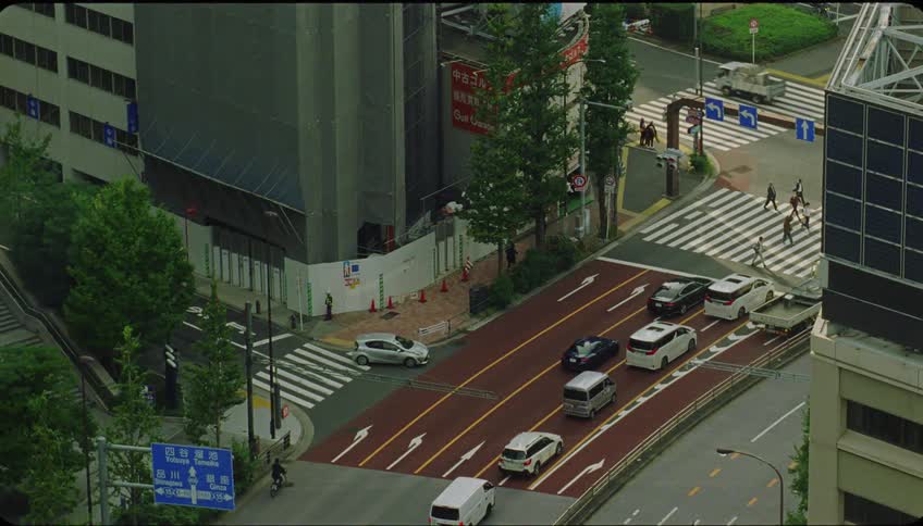 Top view of cars stopped at a traffic light with pedestrians in a metropolis