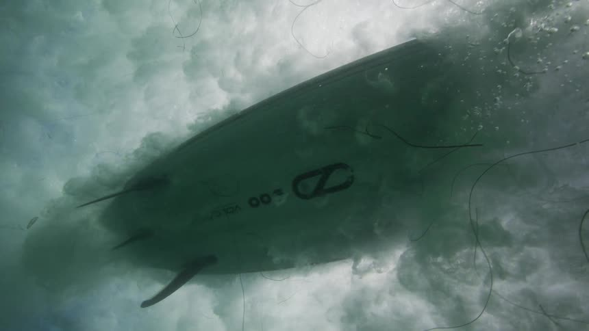 View from inside the sea of a surfboard gliding through the crystalclear water in the daylight