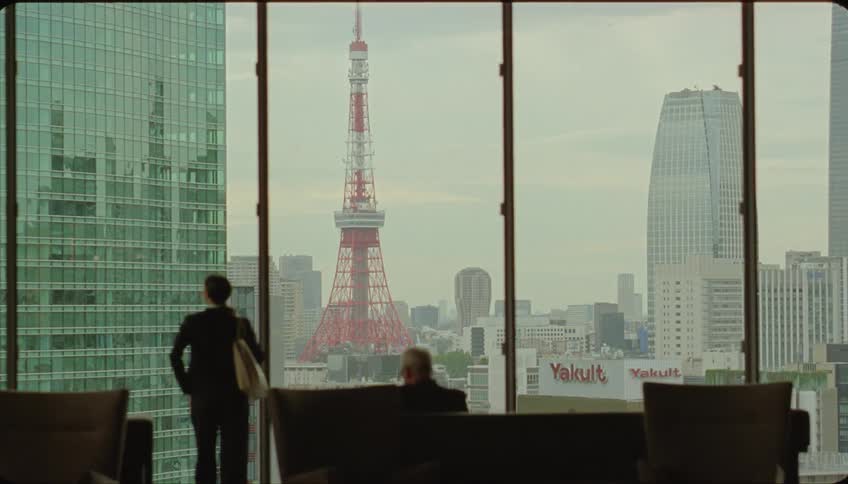 A man sitting and a woman standing observing a metropolis from a building during the day