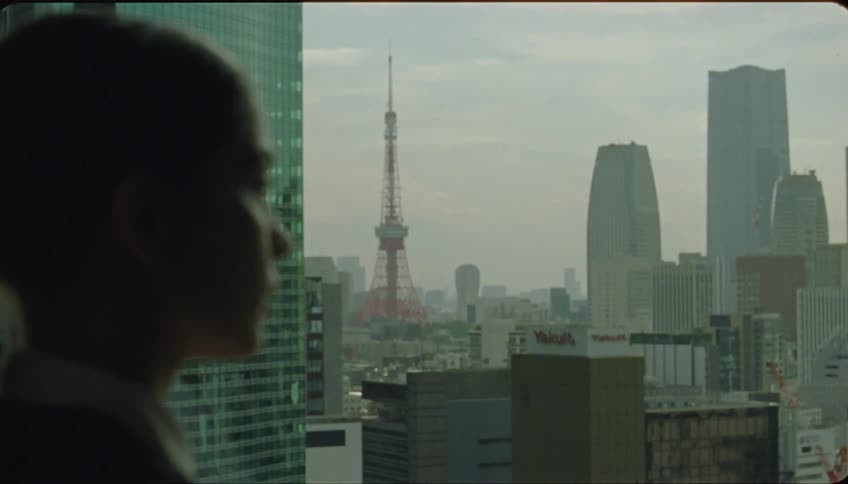 Thoughtful woman looking at the view of the city ahead through the office window until she is interrupted by someone calling her