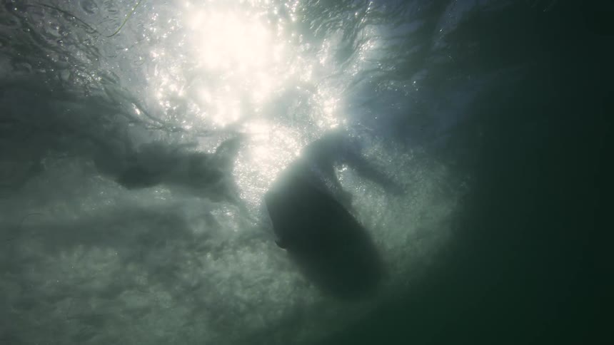 A man surfs a wave at the surface of the water