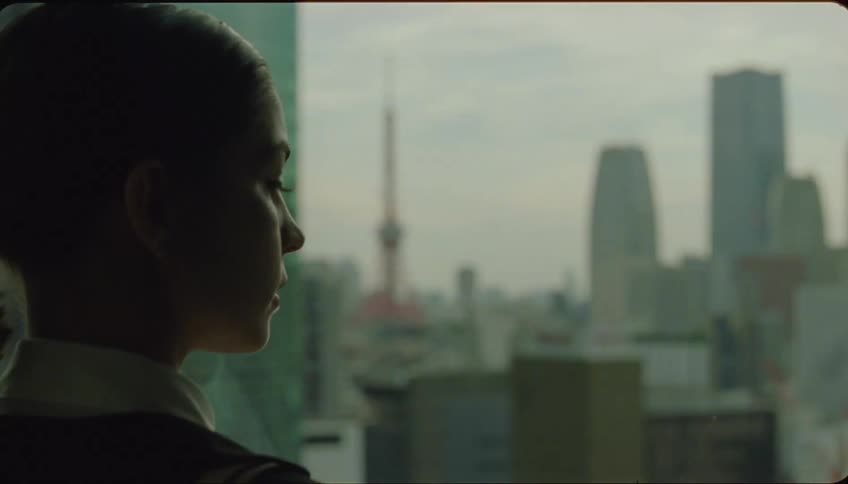 Portrait of a young woman looking out of a building window at the metropolis followed by her walking away with a smile