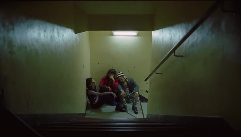Three friends sit at the bottom of the stairs talking