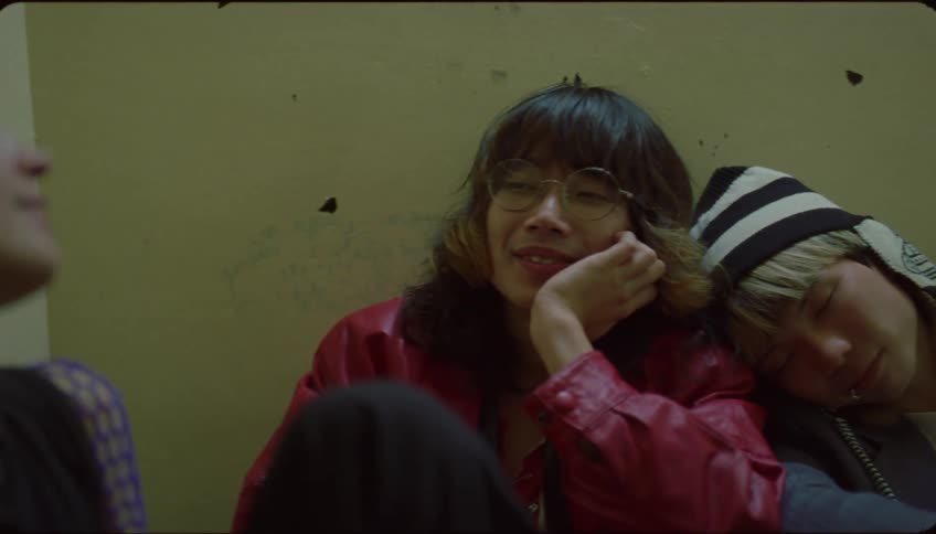 Three teenagers sit against the wall