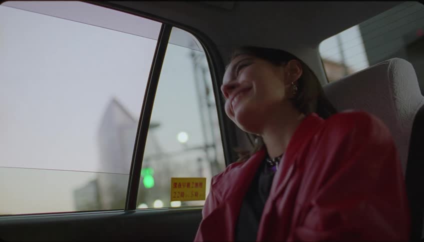 Happy woman waves goodbye from the back of a moving vehicle