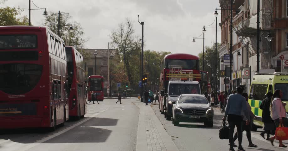 View of a street in the midst of a metropolis with cars and buses stopping for pedestrians to cross the road