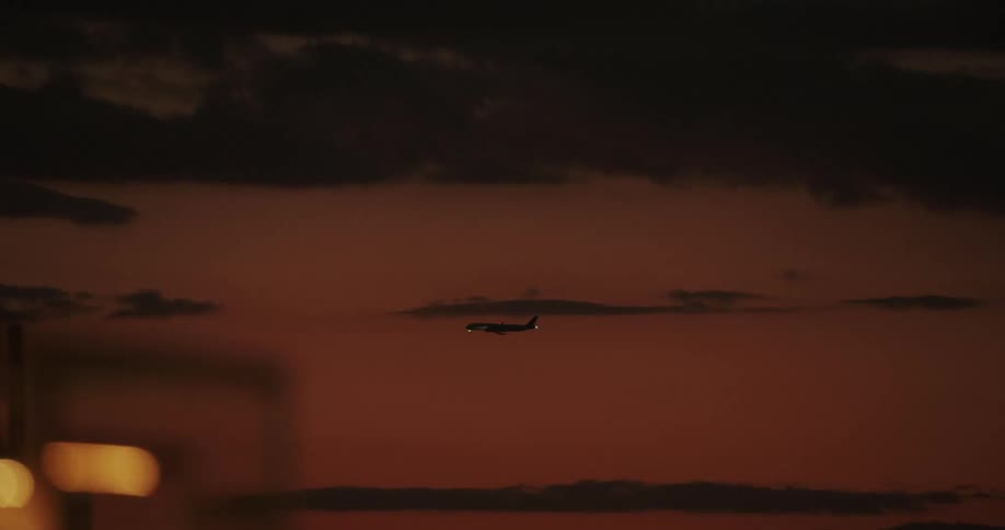 Airplane landing against a red dawn sky