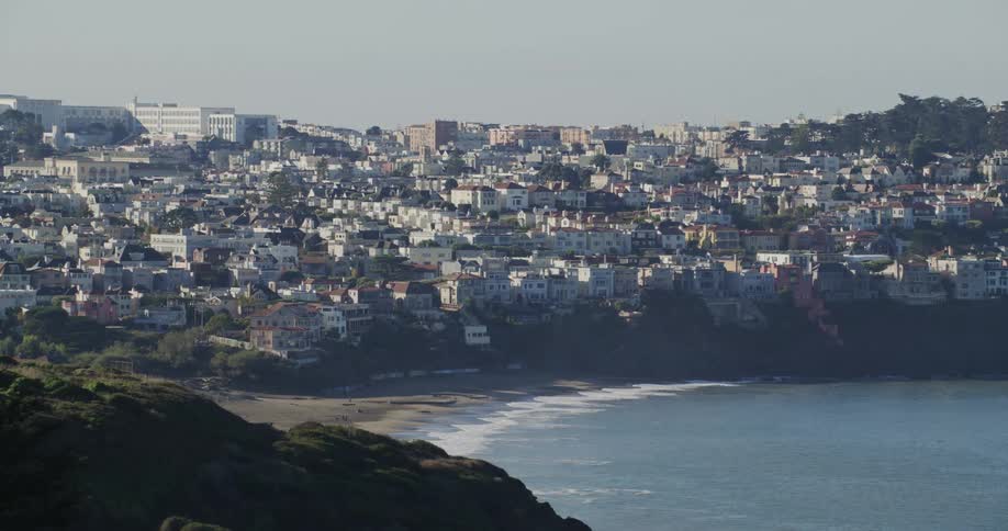 A wide sandy beach with a city skyline in the background