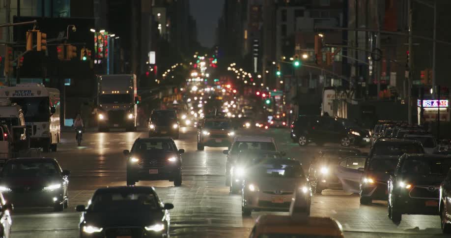 Pedestrians and vehicles move through busy city streets at night