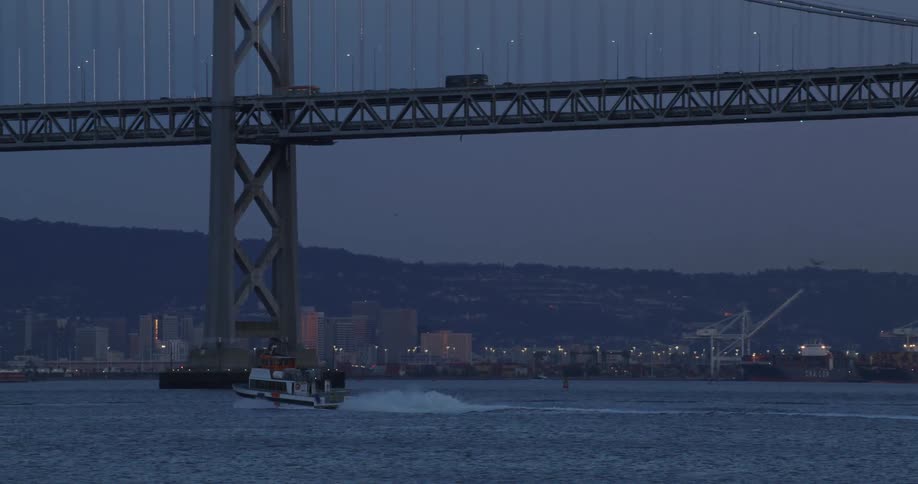 A boat moving on the sea in a metropolitan area at dawn