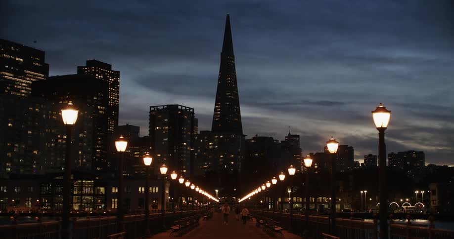 People walking on a boulevard at dusk in a downtown area of a city