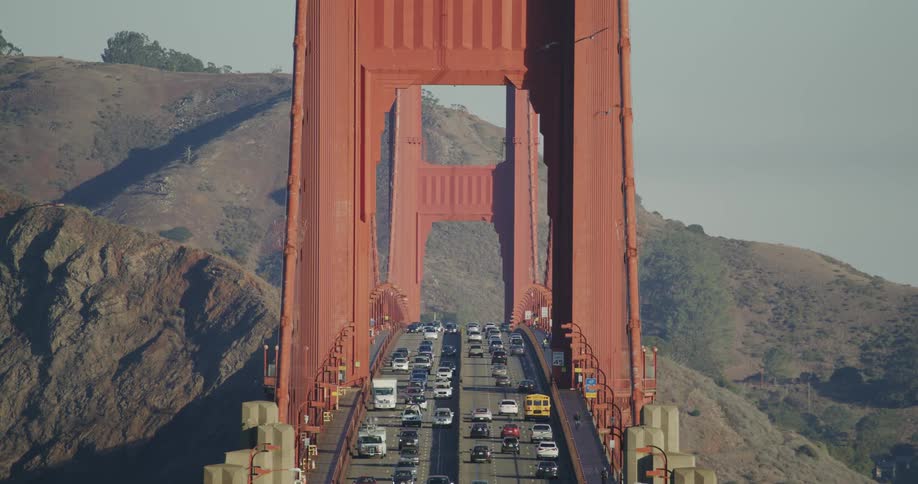 A line of vehicles moves across the iconic golden gate bridge under a clear blue sky