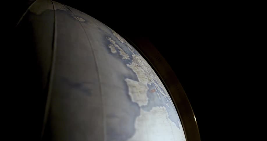 Light shines on a globe in the darkness as it turns