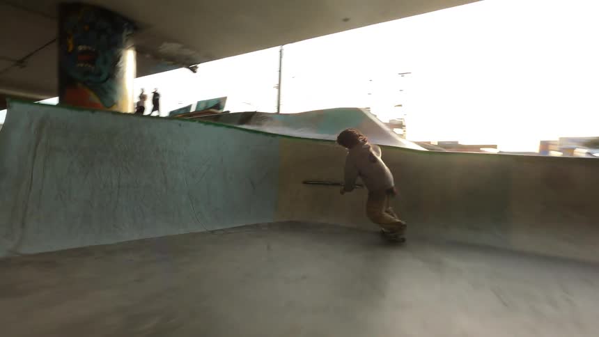 Skateboarder performing tricks on a ramp under a viaduct