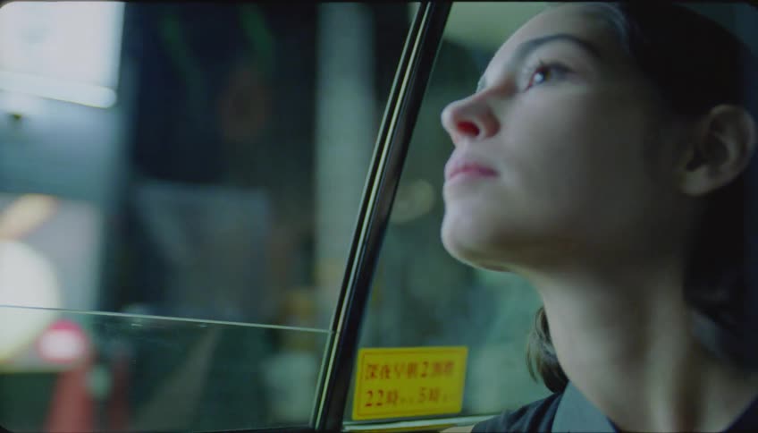 Woman sitting in the back seat of the car contemplating the city view through the window