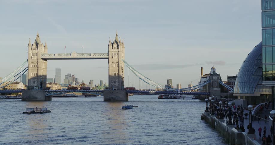London bridge over the sea with vehicles passing and people walking on the shores in a metropolis