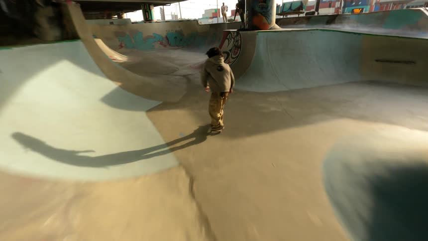 People stand as skateboarder skates graffiti covered skate bowl