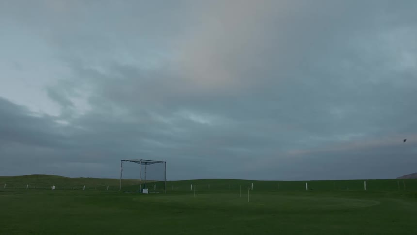 A golf course sprawls across the landscape green fairways lined with trees and dotted with sand traps