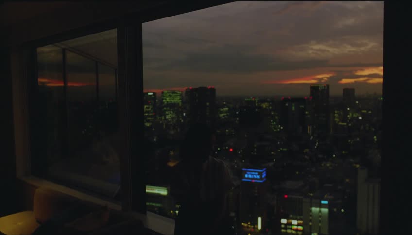 Woman talks on the phone looking at the city from her apartment