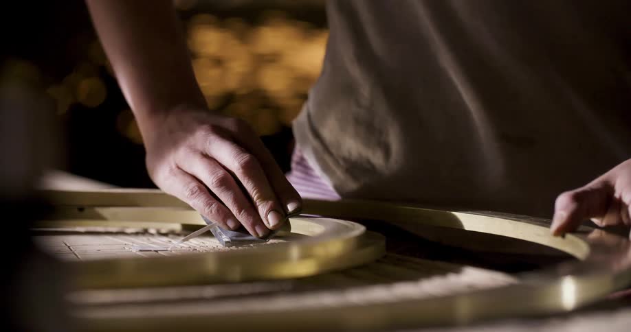 Hand sanding a metallic ring in the workshop