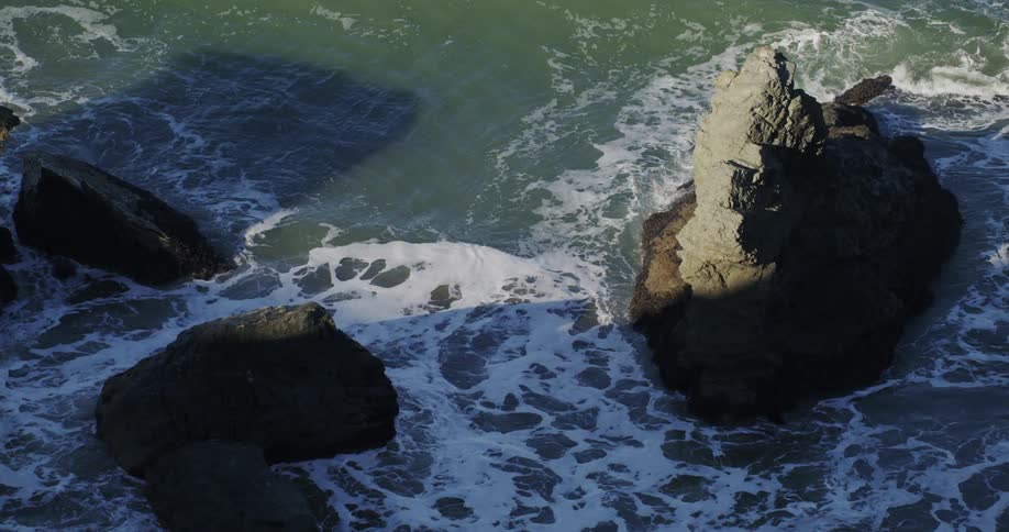 A rocky shoreline with waves crashing against the rocks on a sunny day