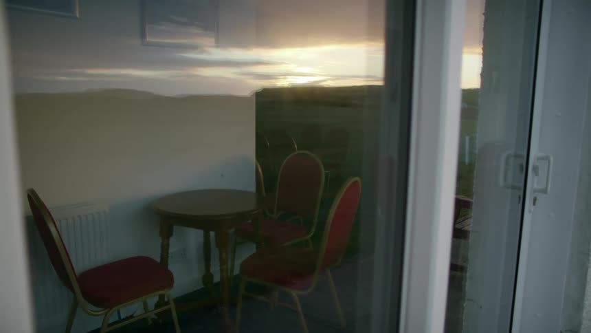 Sliding door glass of home reflects sun setting on the horizon