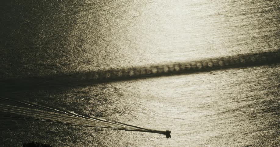 Boat moving near the shadow of a bridge on a river