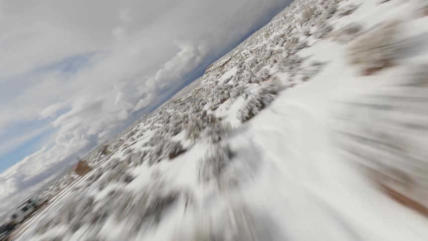 Fenced field borders snow covered canyon on a cloudy day