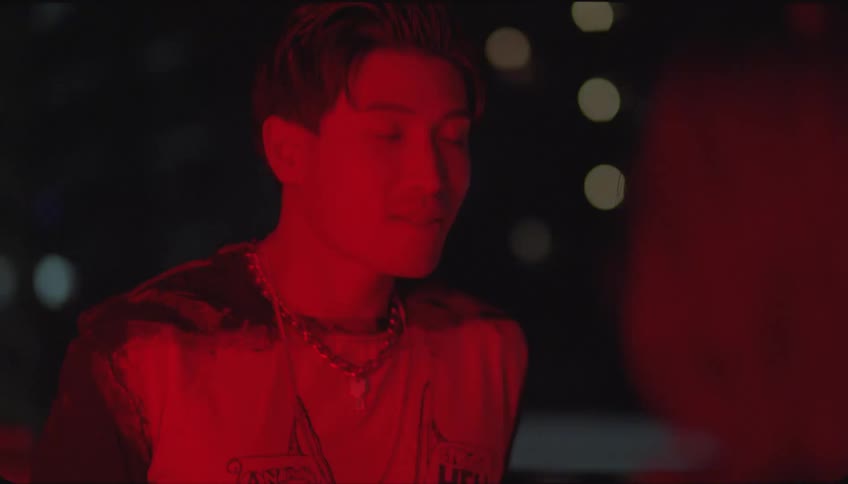 A man smiling and talking to someone takes off one of his shirts and the entire environment is in red colors