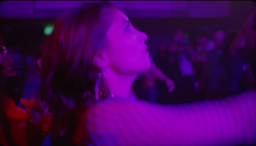 A young woman jumping and dancing at a party in a night club