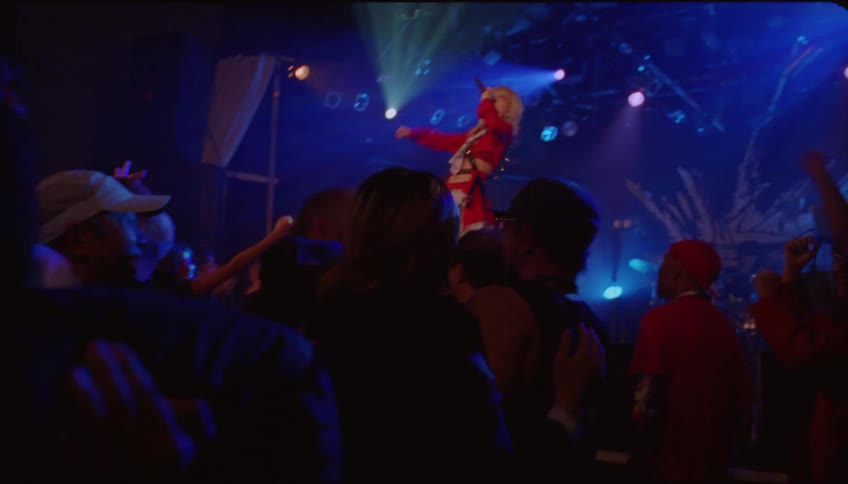 People dancing at a concert while a lady sings on stage at night