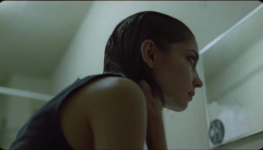 A woman smooths her hair while looking in a bathroom mirror