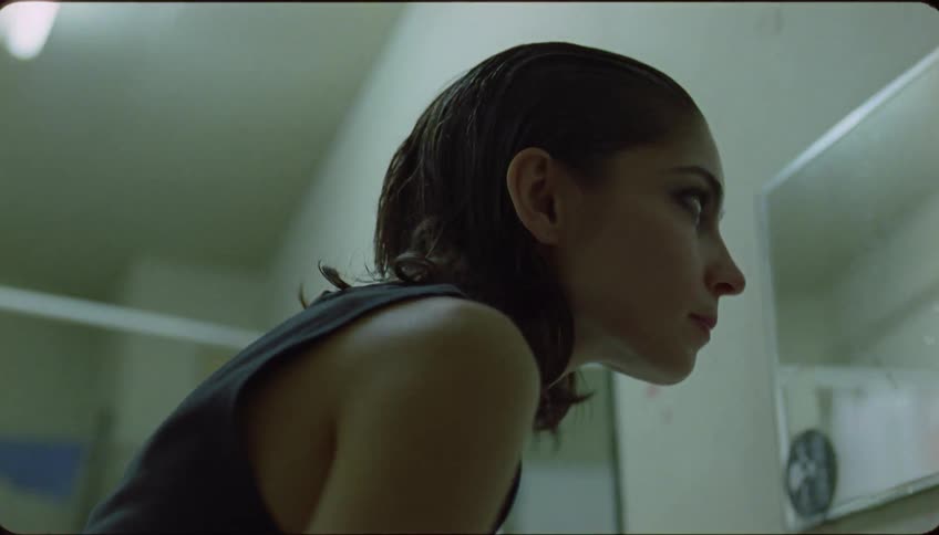 A woman runs water through her hair in the bathroom